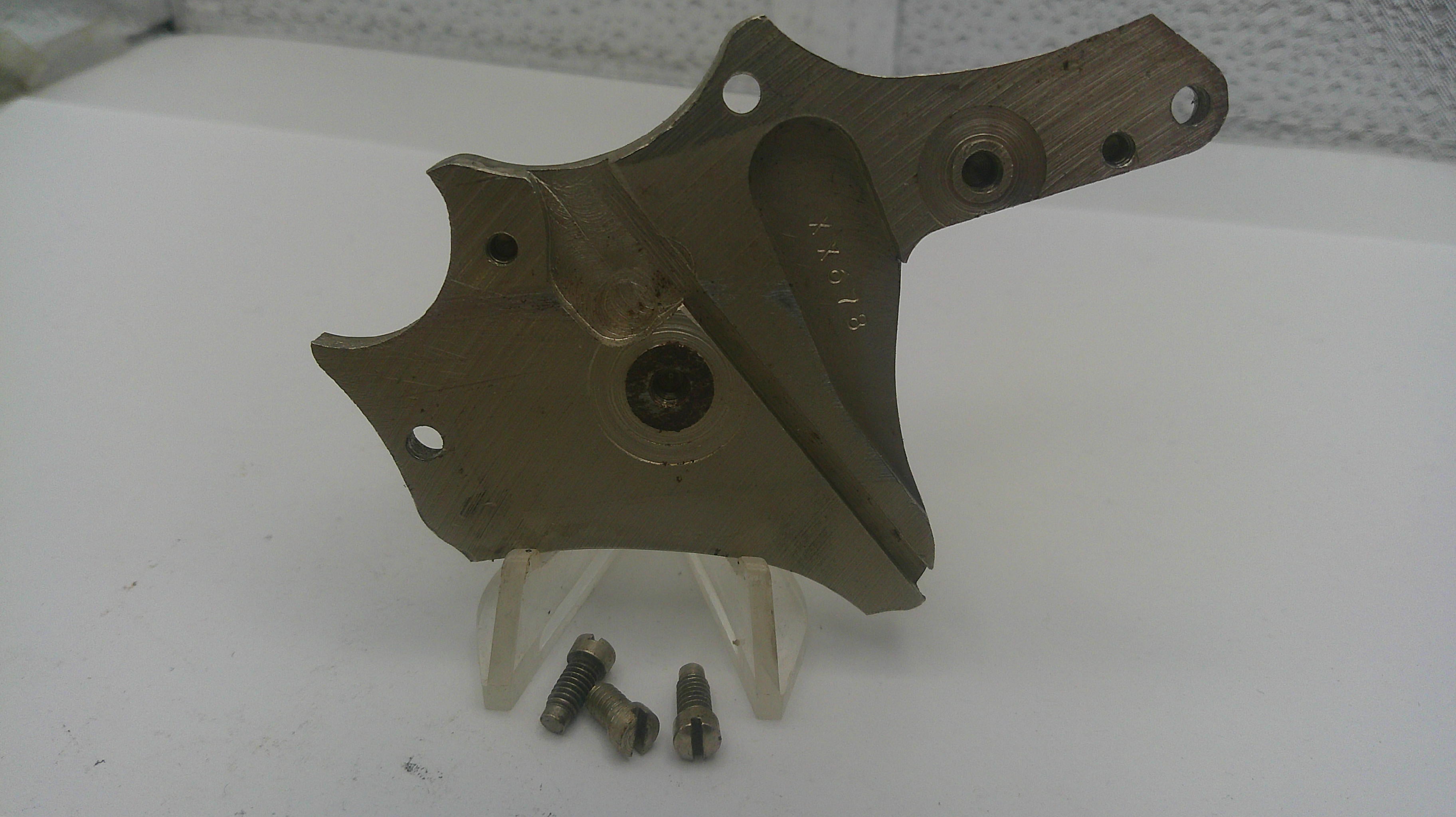 Metal mechanical component on a white surface with small metal parts.