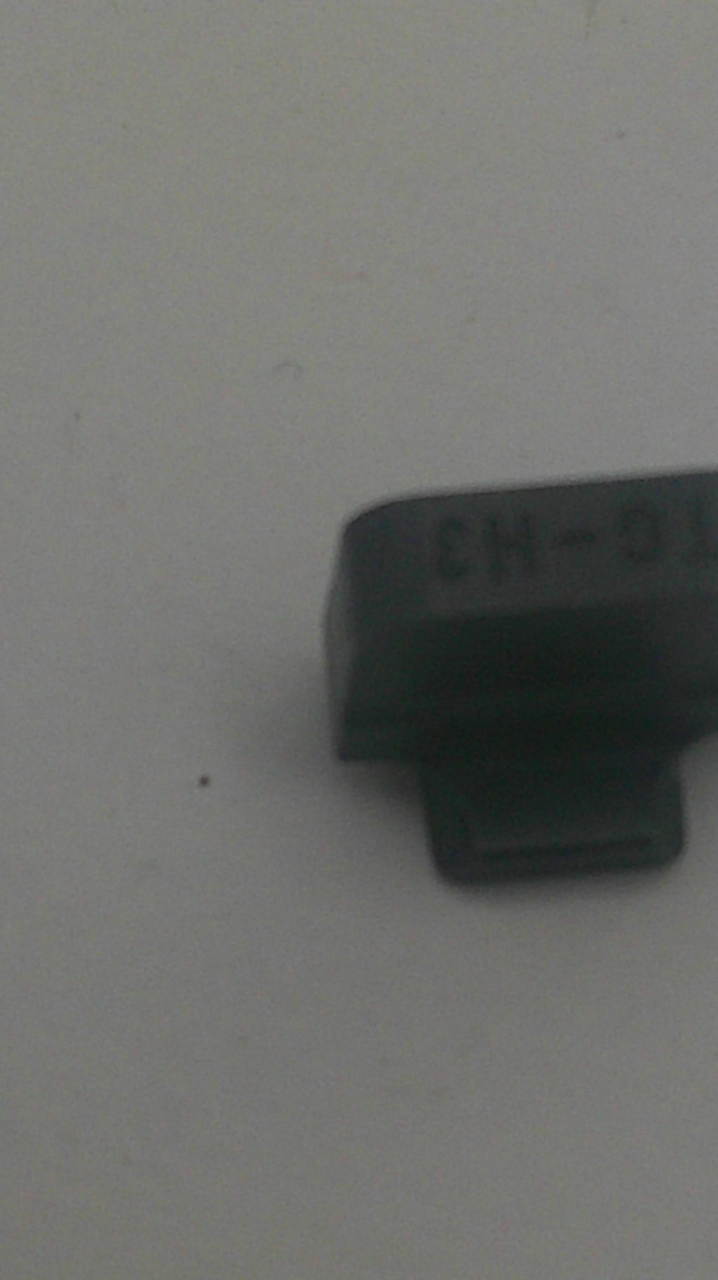 A small black plastic automotive relay component with molded text 'L6-H3' on its side, photographed against a plain light gray background.