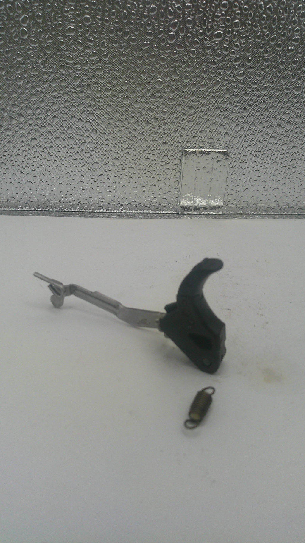 A fishing lure weight and black hook with a metal leader, shown against a split white and textured gray background.