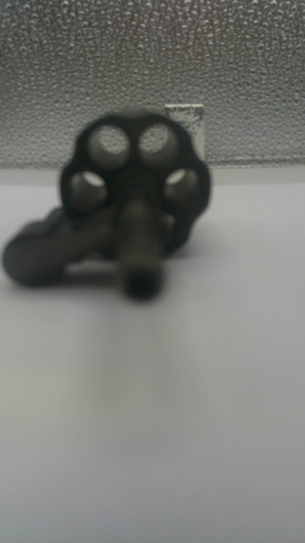 A close-up of a black multi-gang revolver keyhole mounted on a textured gray door next to a plain white surface.
