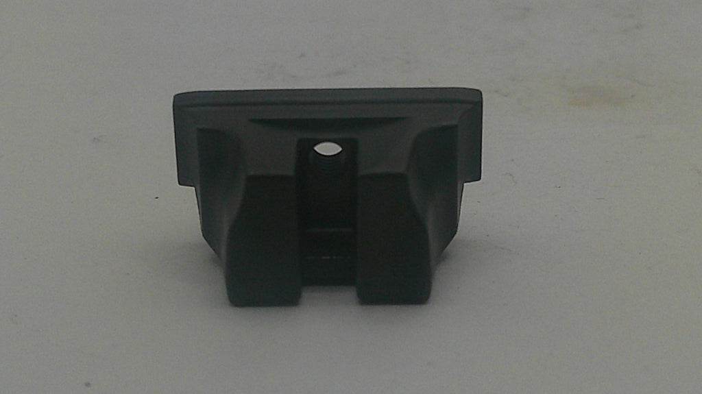A small black plastic component or clip with a rectangular top and two angled side supports, photographed on a plain light gray surface.
