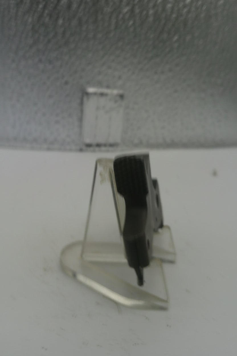 Small black object on a clear stand against a textured white background