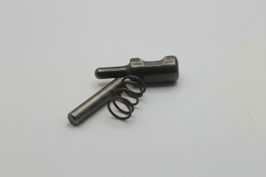 Small metallic object with a spring on a light gray background