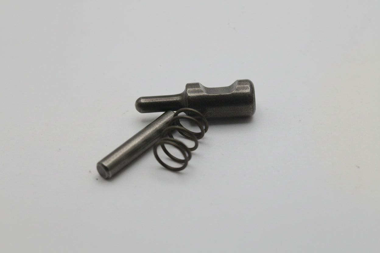 Small metallic object with a spring on a light gray background