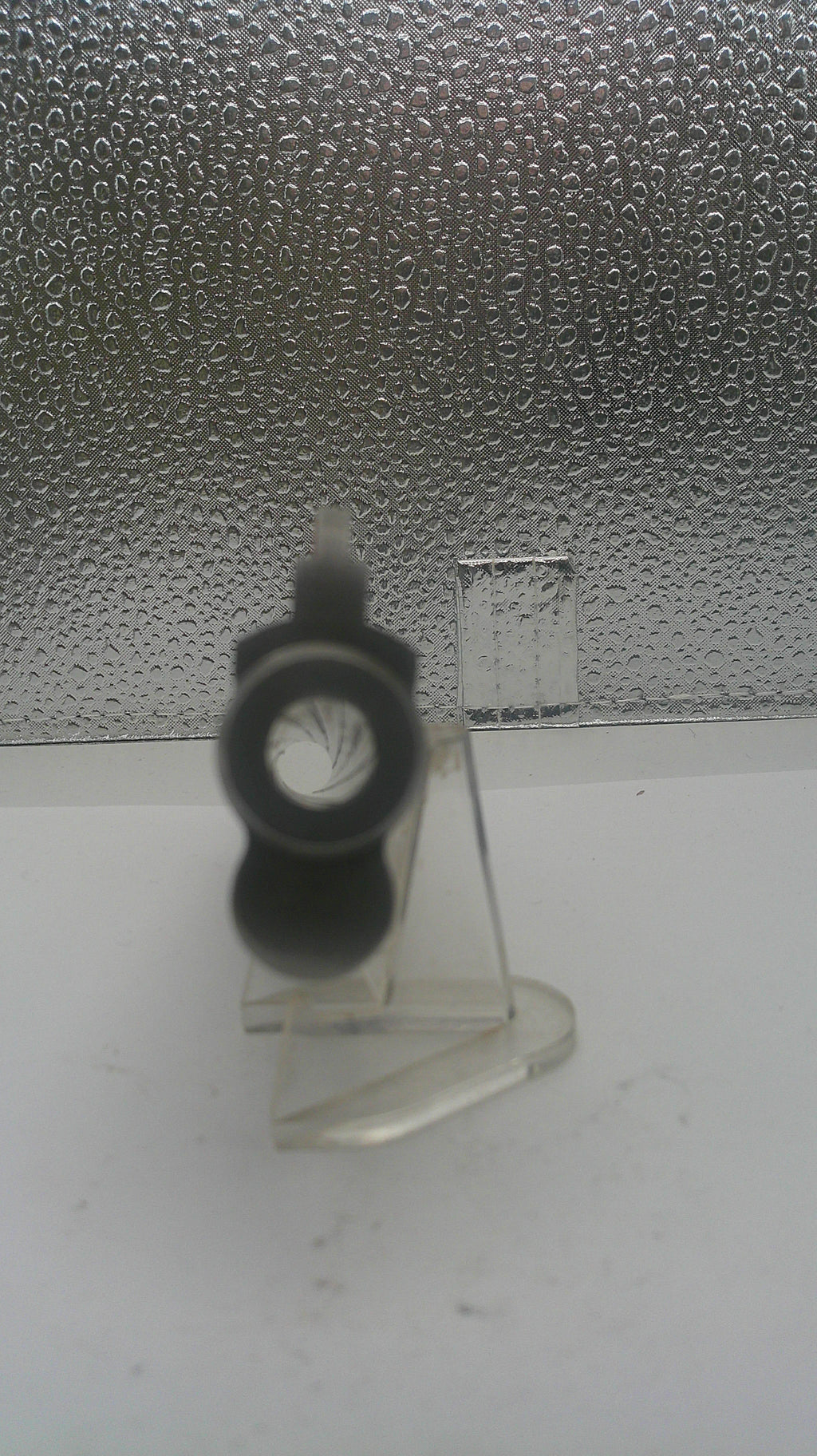 Clear plastic hook with a black rubber washer on a textured surface
