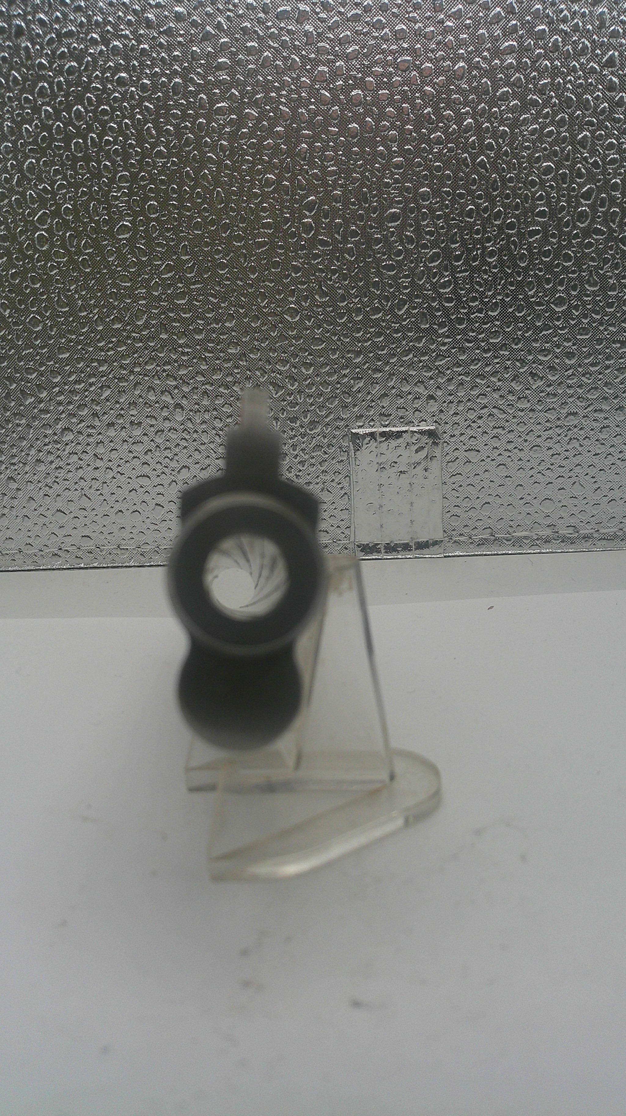 Clear plastic hook with a black rubber washer on a textured surface