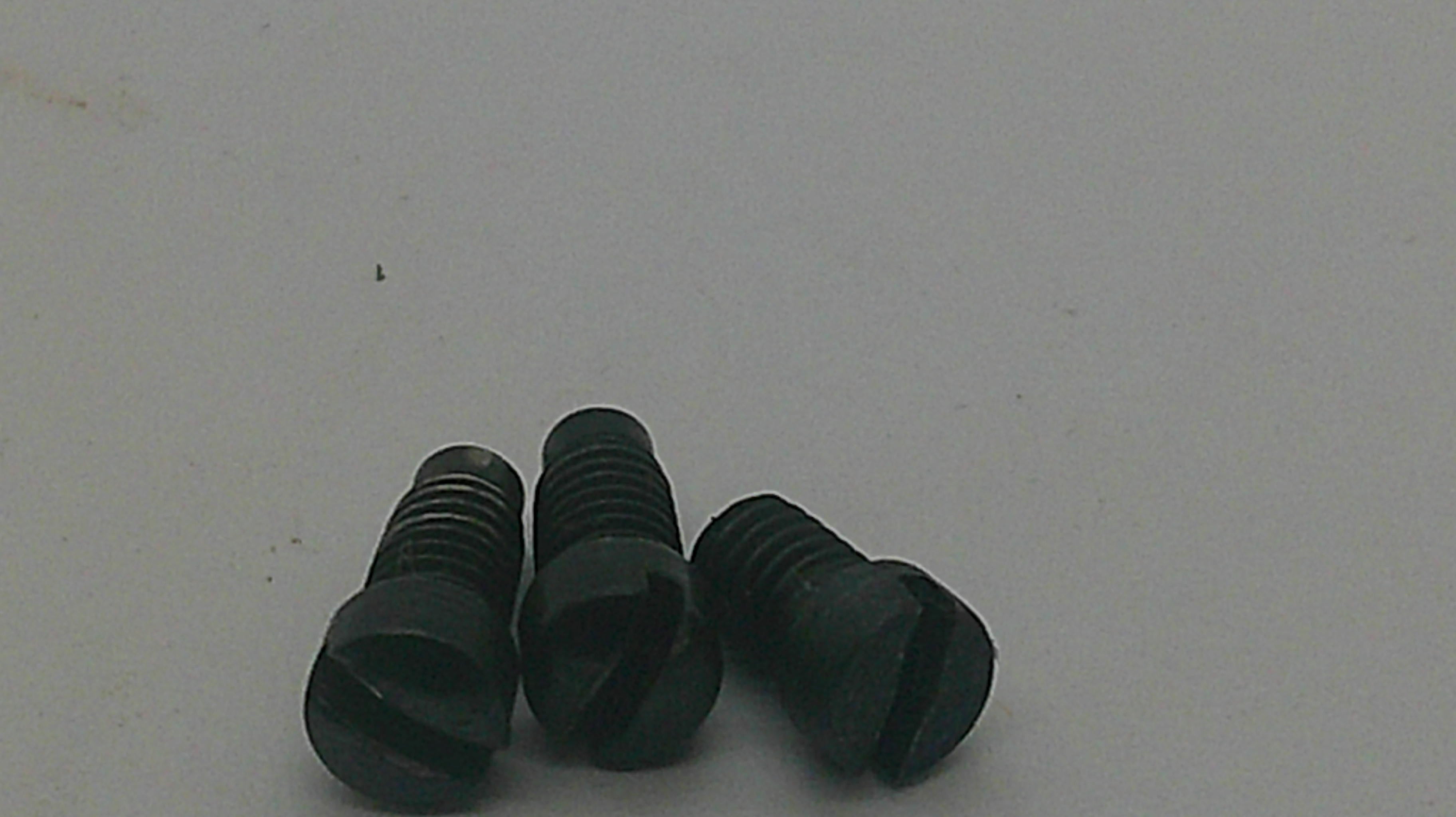 Three small black slotted flat head screws on a plain light gray background.