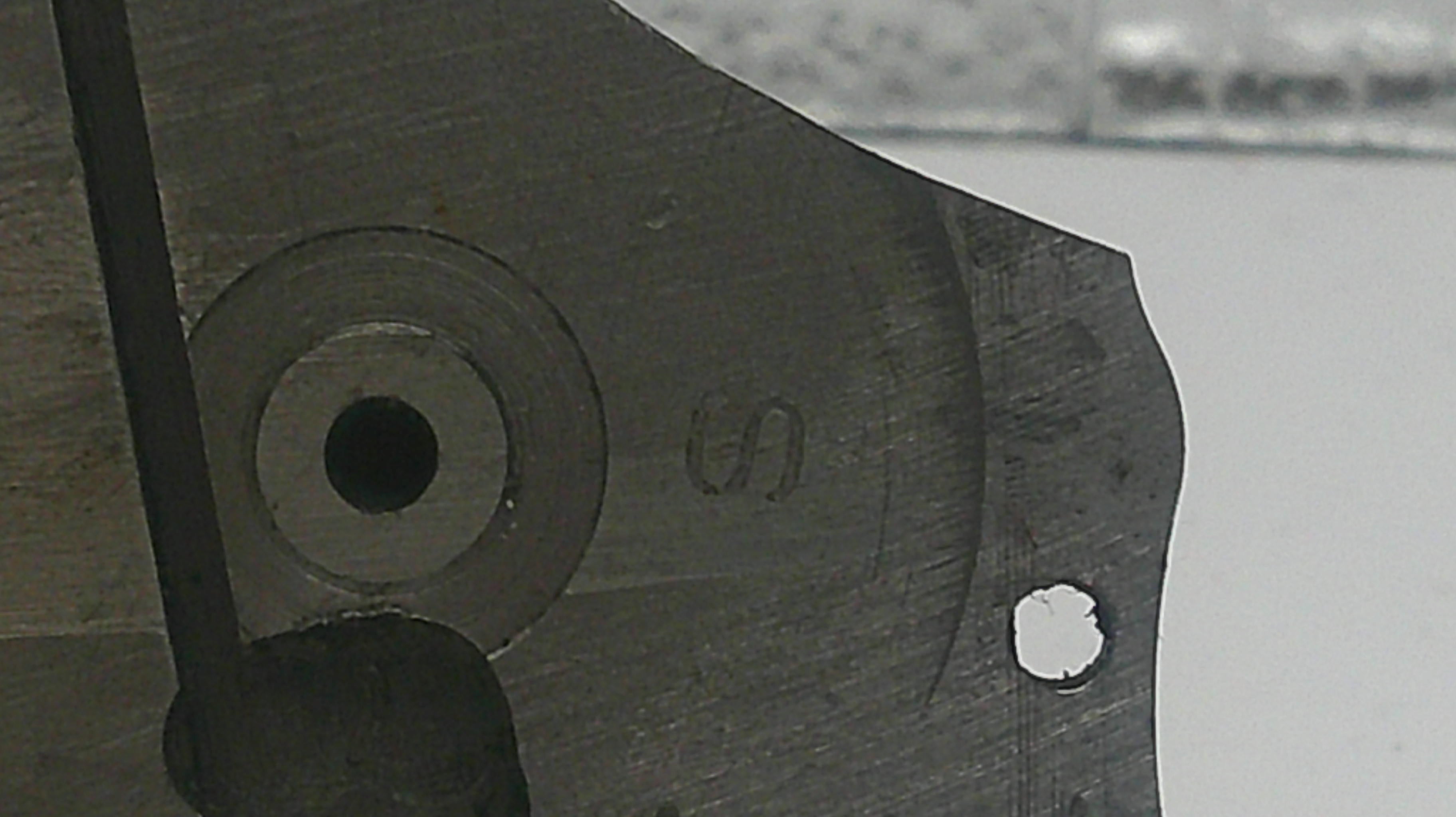Close-up of a metal tool with a circular hole and 'S' marking on a blurred background