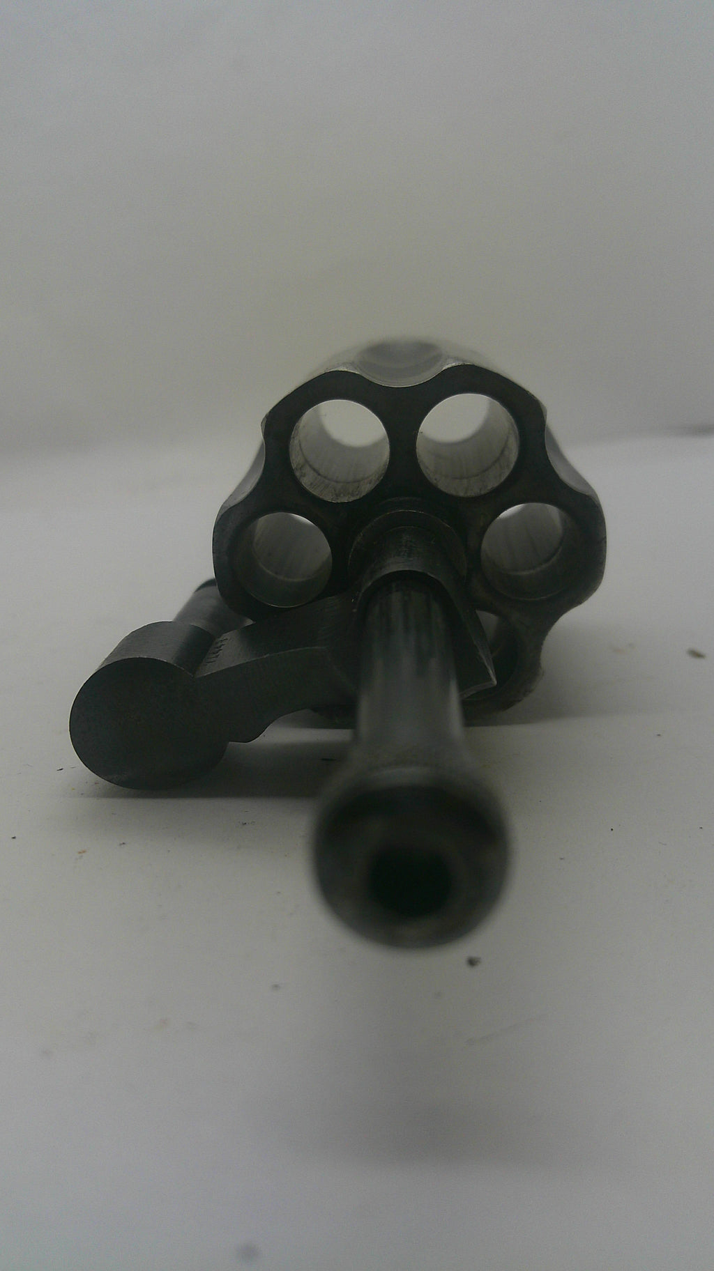 A black metal revolver-style accessory or component photographed against a plain light background.