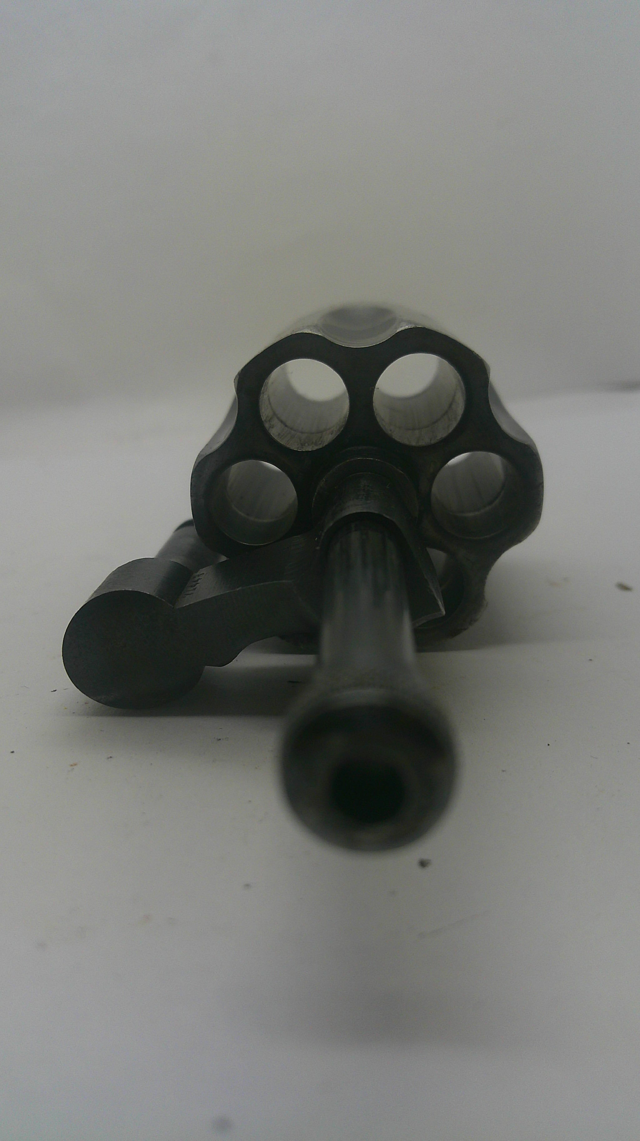 A black metal revolver-style accessory or component photographed against a plain light background.