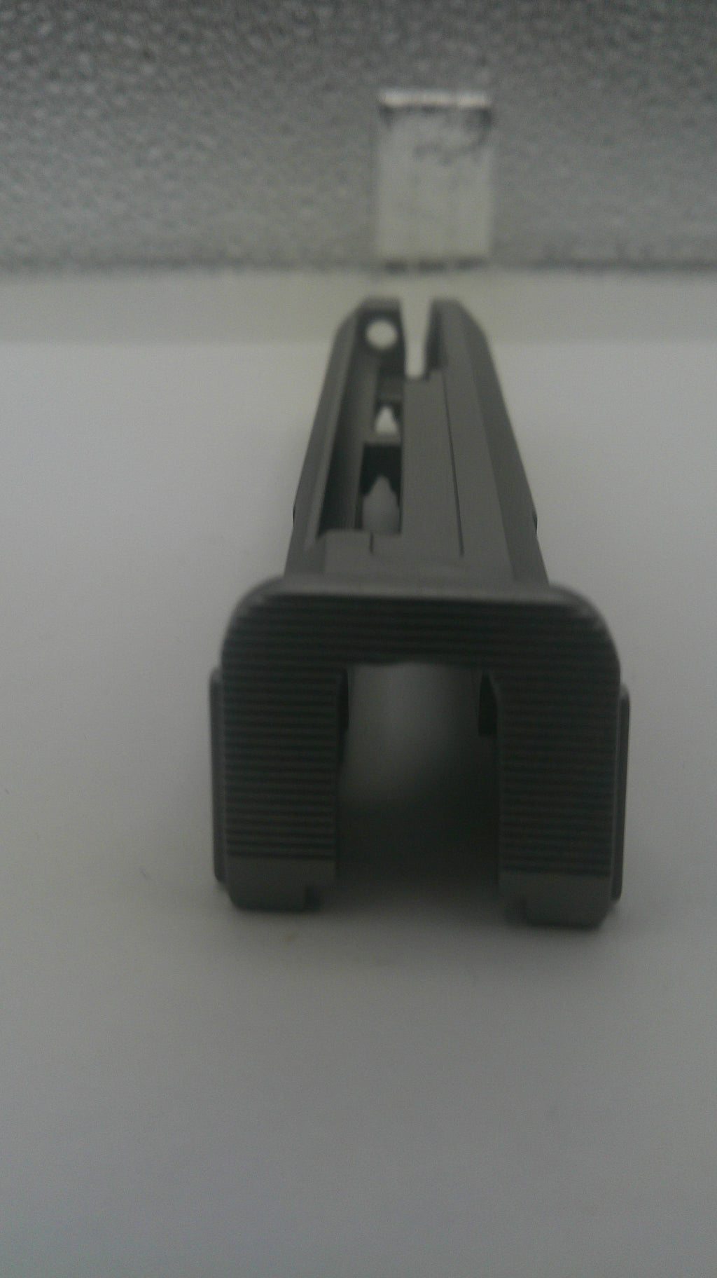 A dark gray plastic mounting clip or bracket shown on a plain light background.