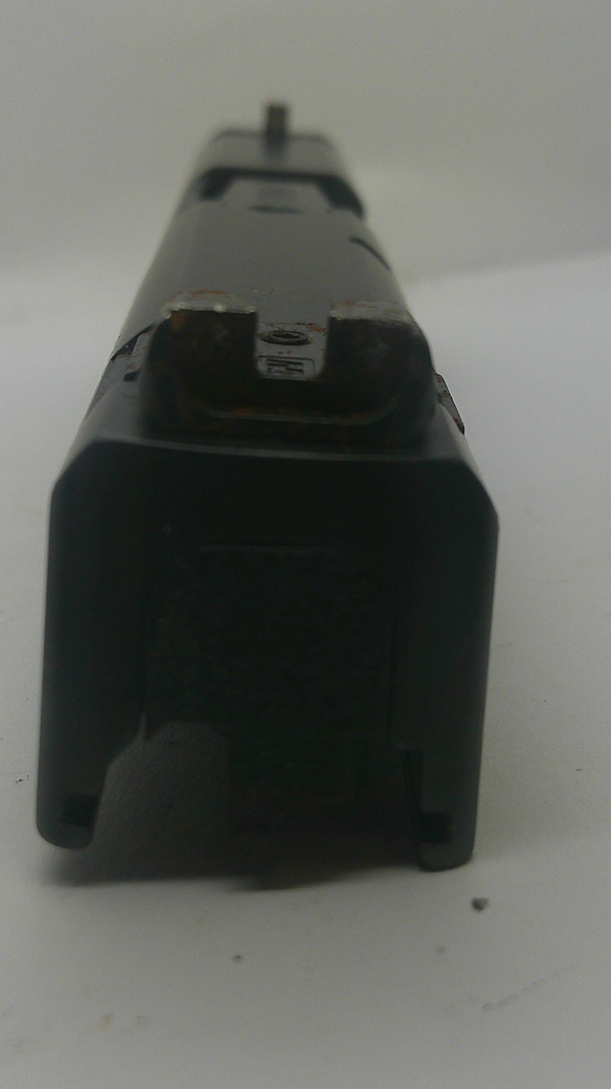 A close-up of a black plastic component or tool part on a plain white surface.