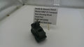 Black firearm part on a white surface with a label indicating brand and model details.