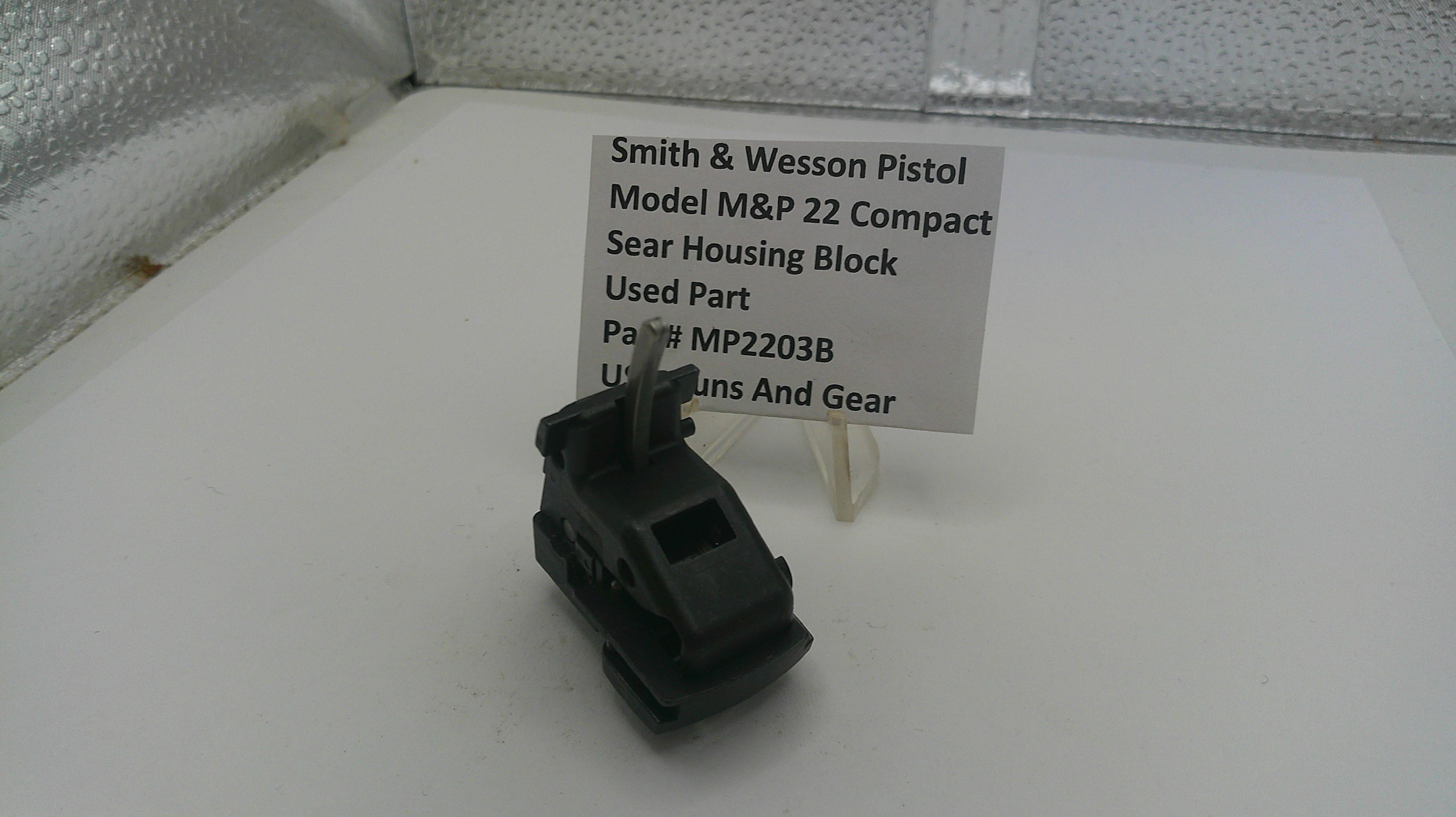 Black firearm part on a white surface with a label indicating brand and model details.