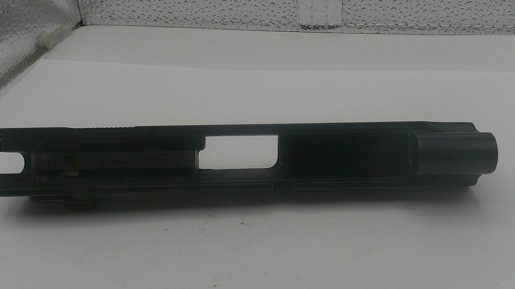 Black metal gun barrel on a white surface with a textured wall background