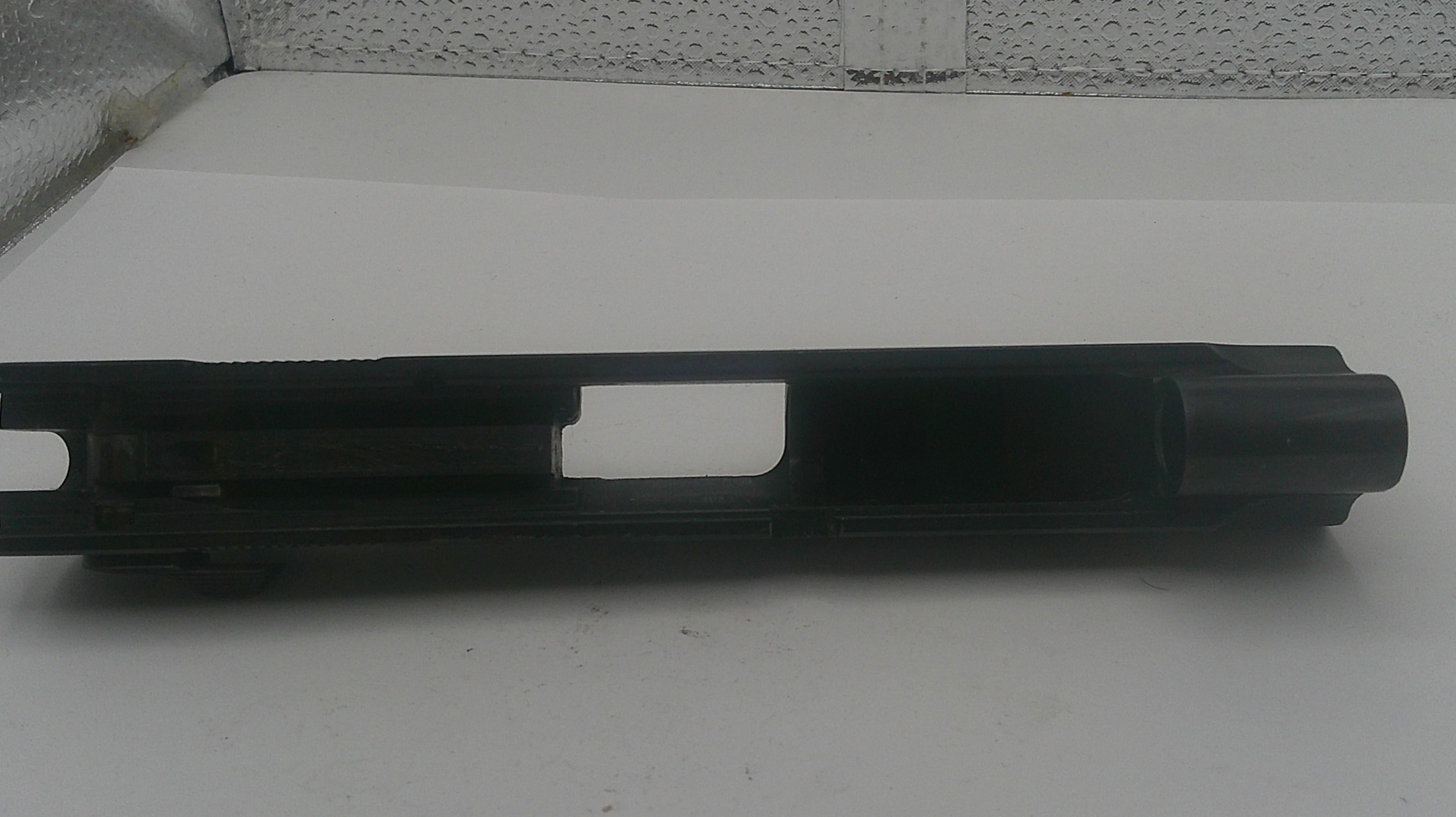 Black metal gun barrel on a white surface with a textured wall background