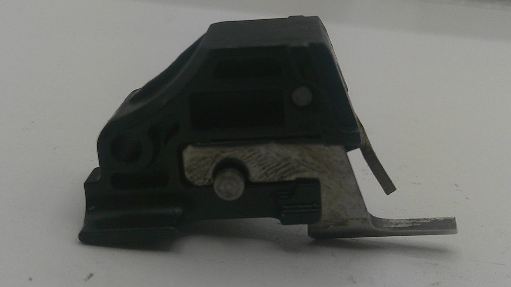 A small black plastic and silver metal mechanical component, likely a latch or switch part, photographed on a plain light gray surface.