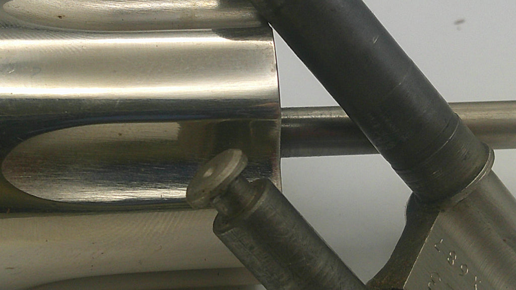 Close-up of metal pipes and a bolt on a reflective surface