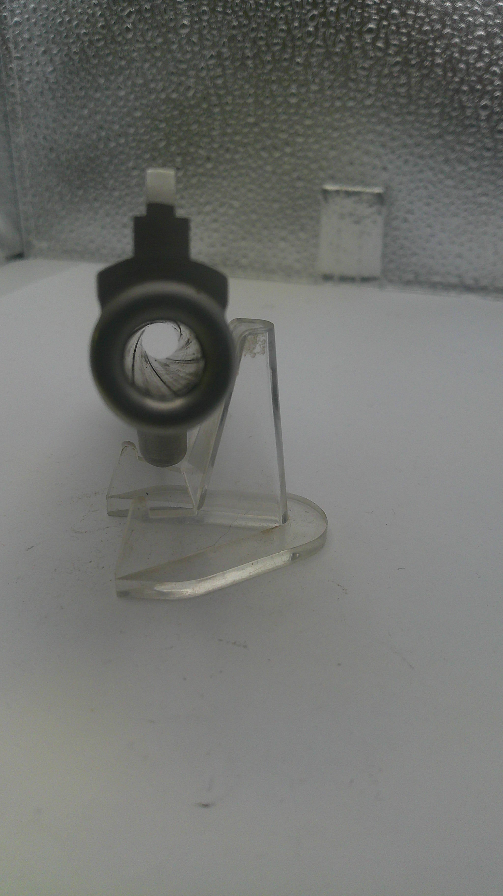 Clear plastic stand with a black circular object on a textured surface