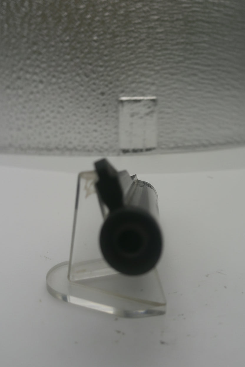 Close-up of a textured wall with a black object on a white surface