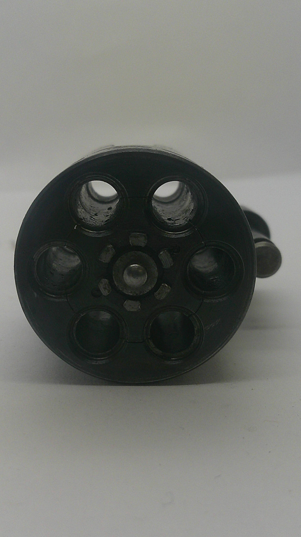 A close-up of a black plastic six-hole revolver magazine or shell holder, viewed from above against a plain light background.