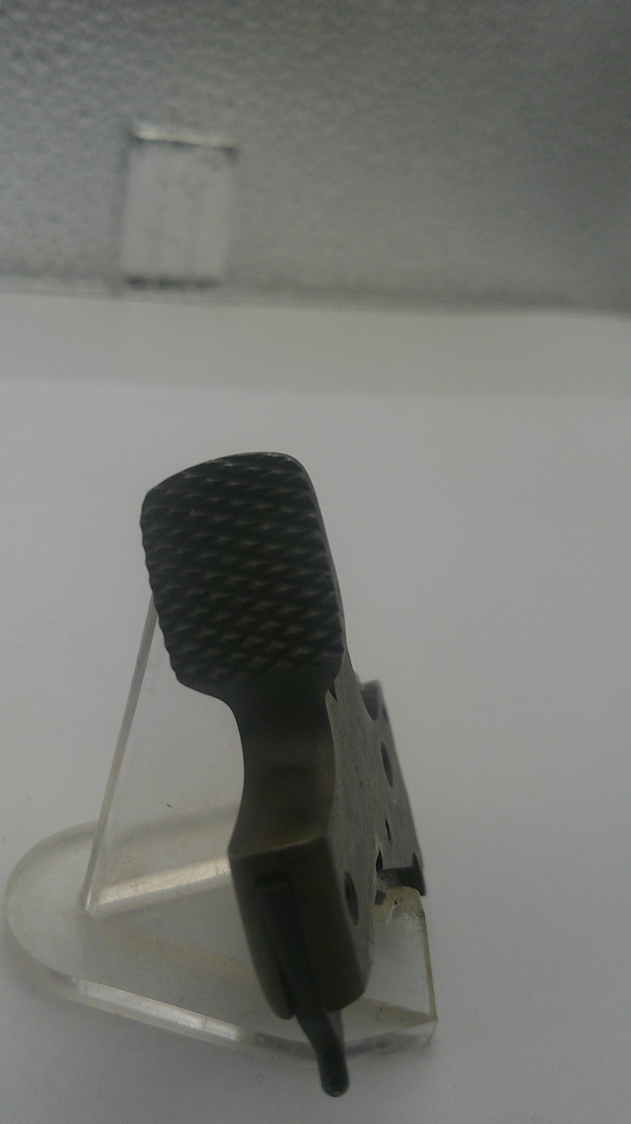 A close-up of a black textured handheld device with a clear plastic mounting bracket attached to a white wall.