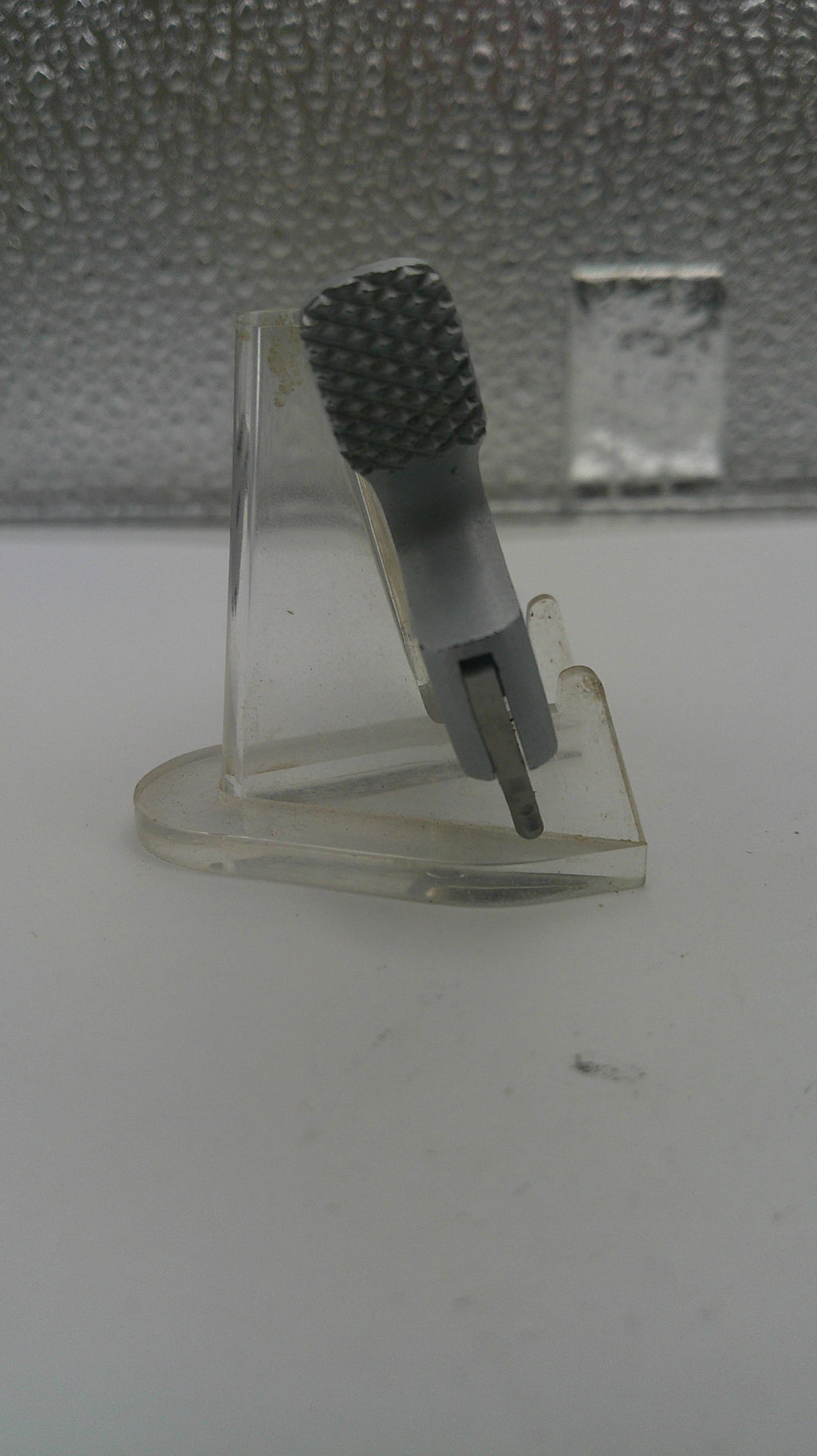 Clear plastic hook with textured gray end on a white surface