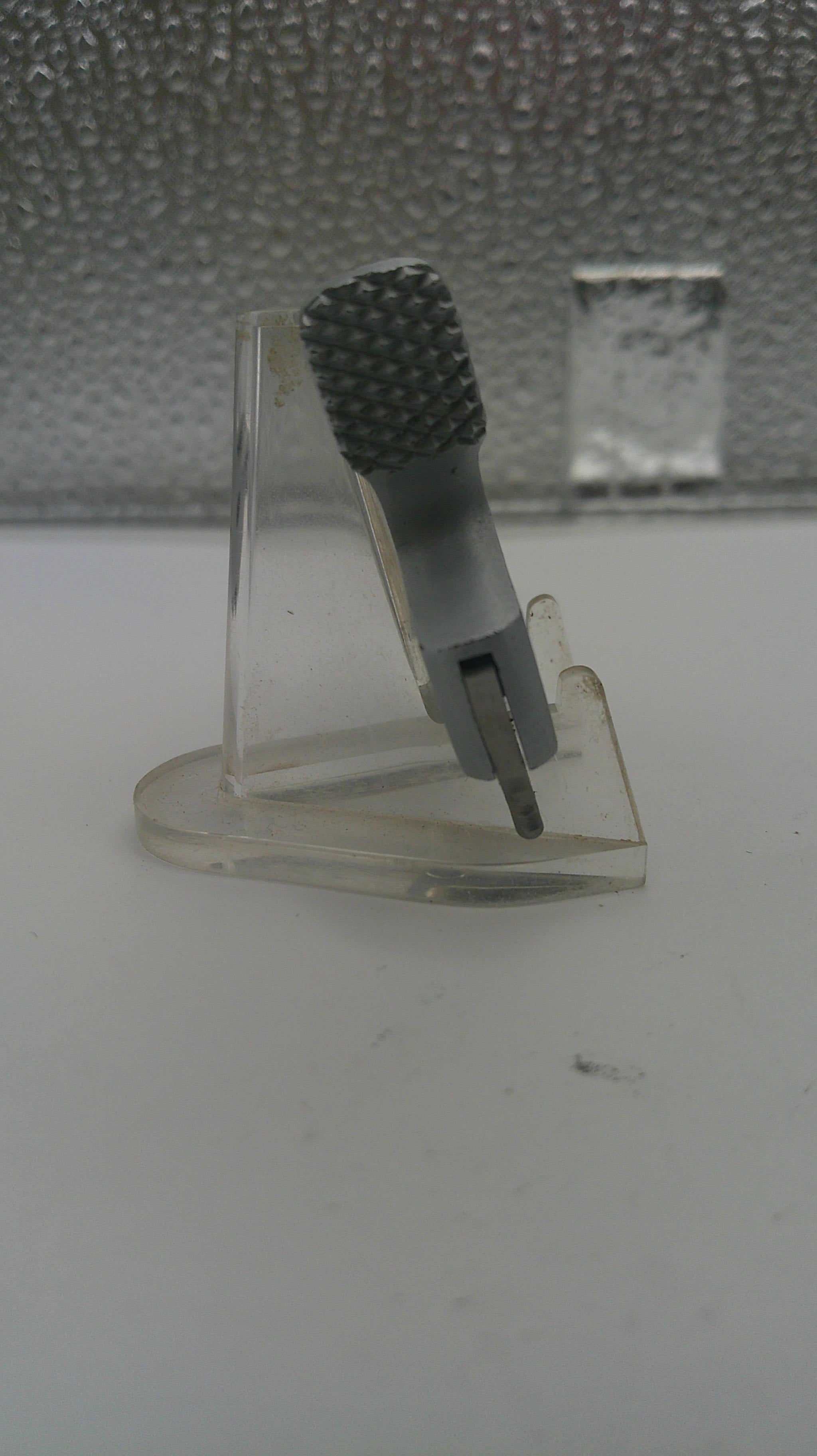 Clear plastic hook with textured gray end on a white surface