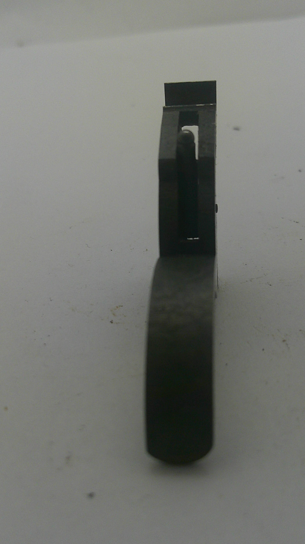 A small black plastic or metal tool component with a curved handle and flat rectangular end, photographed on a plain off-white background.