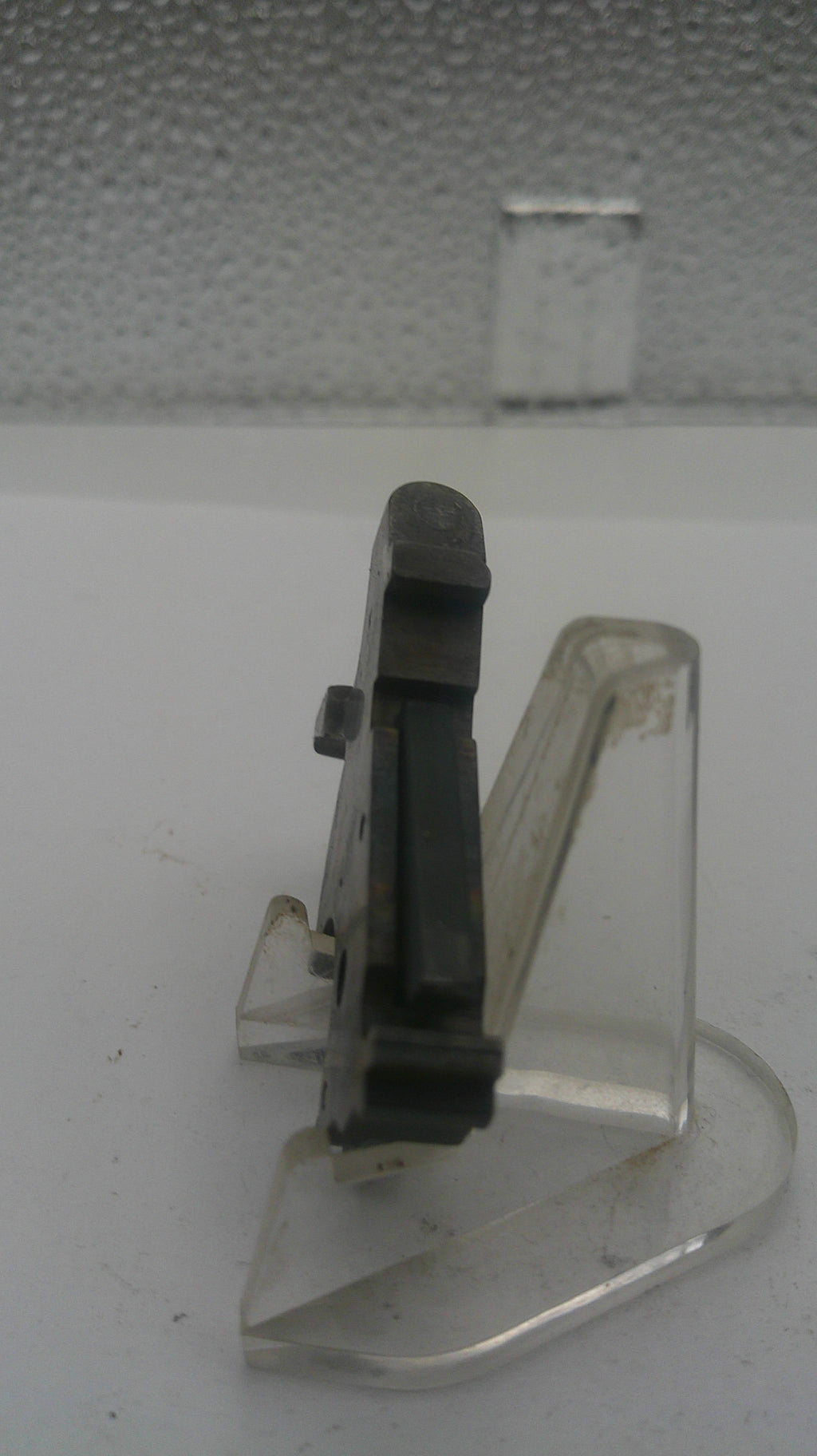 Clear plastic bracket with a black component on a white background