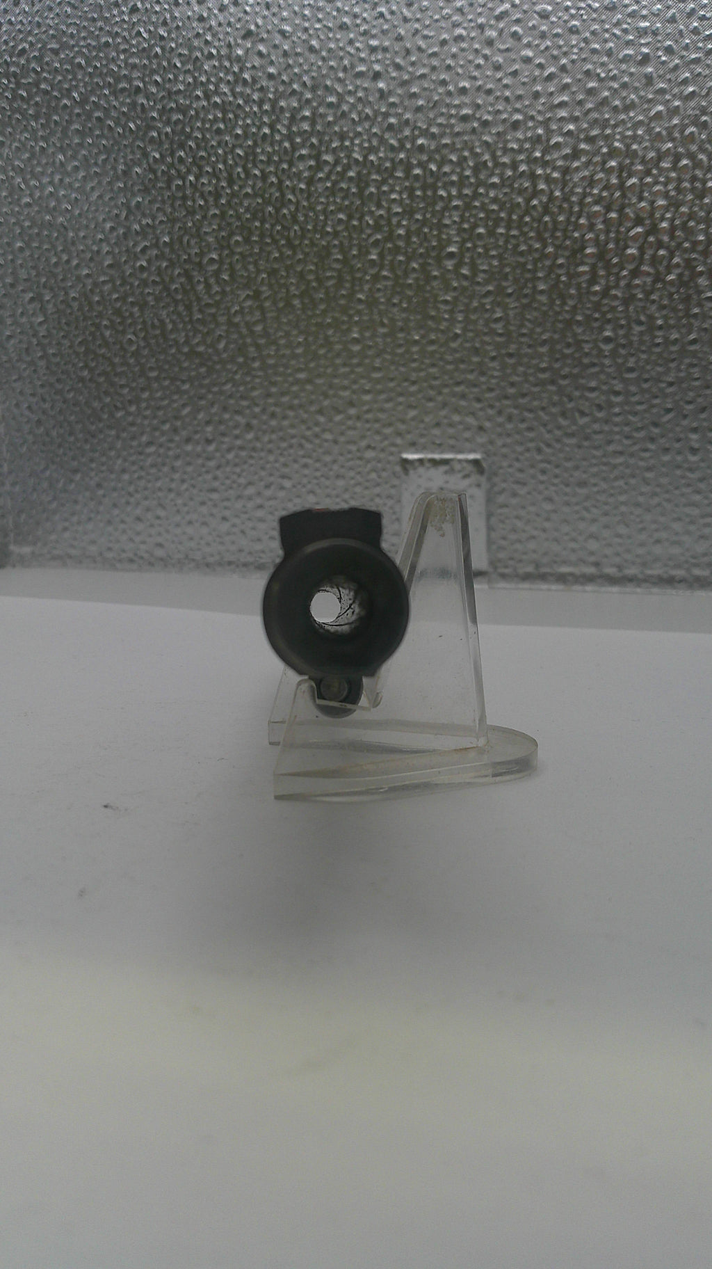 Clear plastic hook with black clip on a textured gray surface