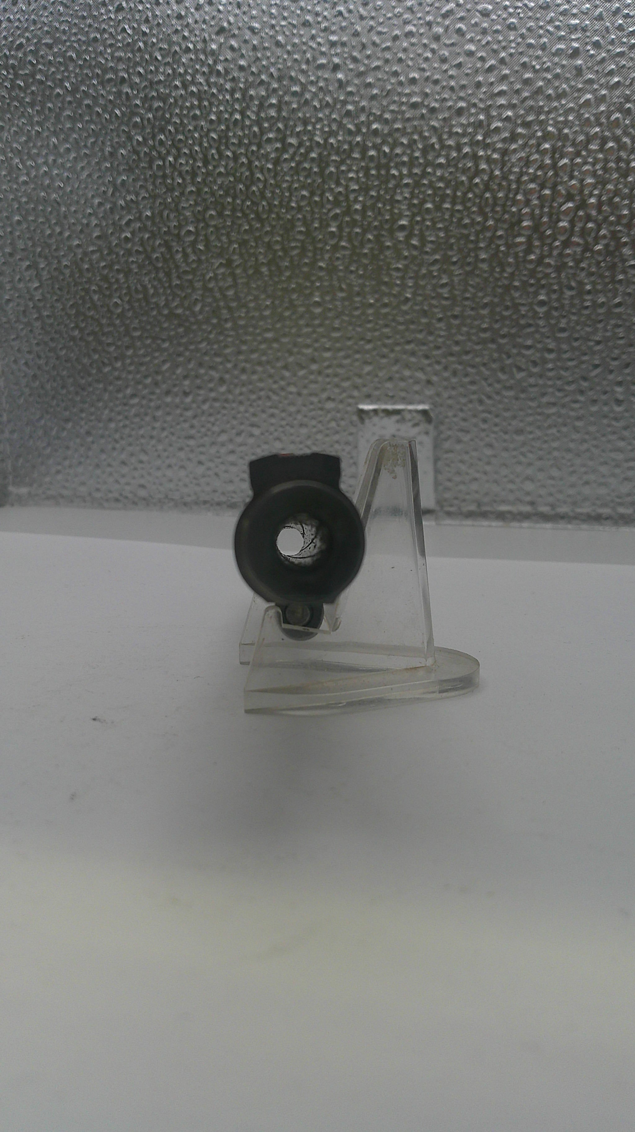 Clear plastic hook with black clip on a textured gray surface