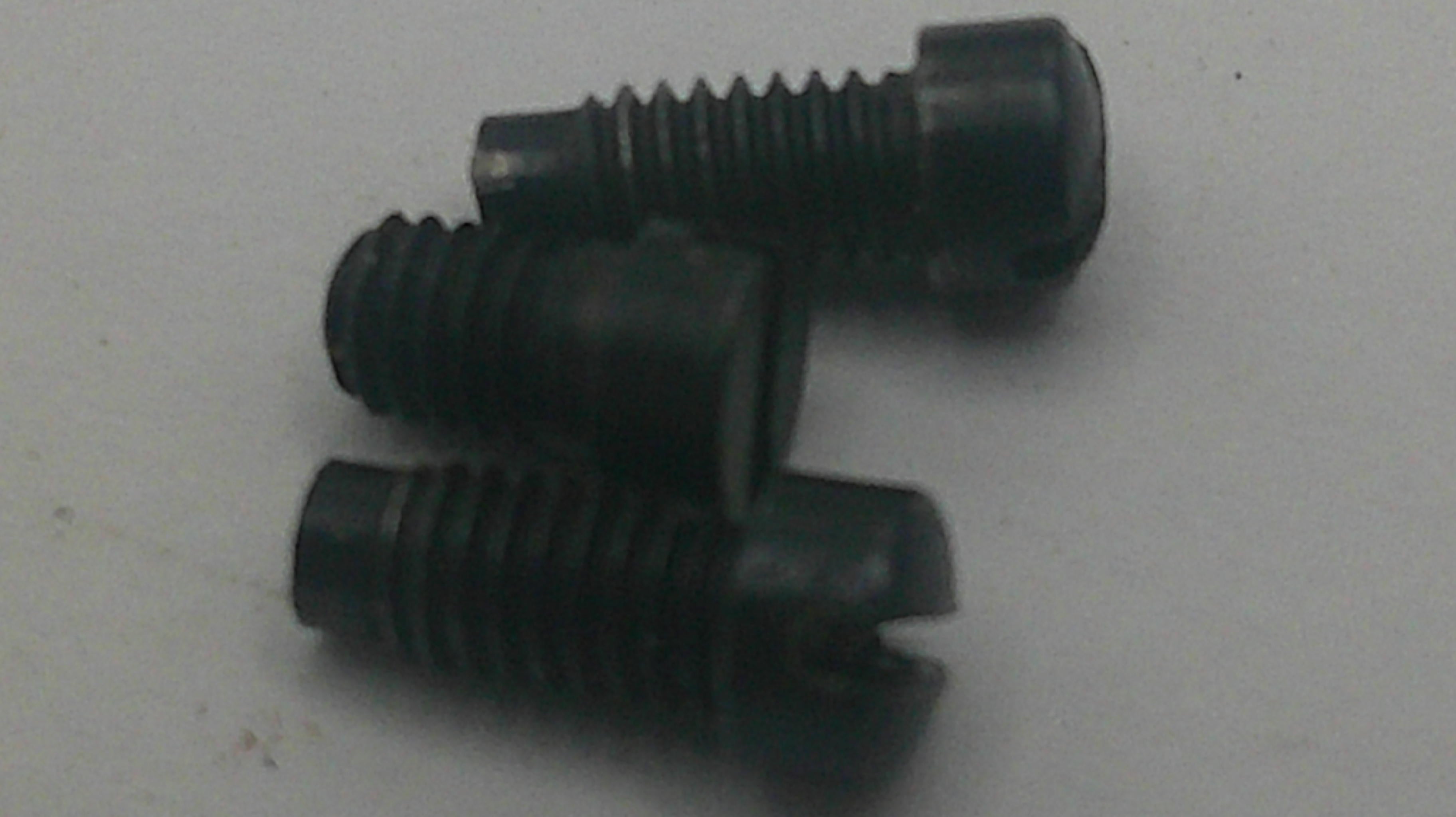 Three black slotted flat head screws on a light gray background.