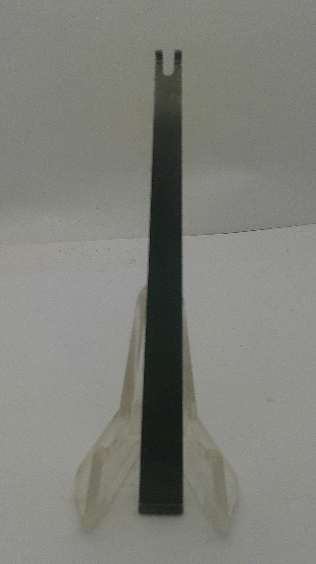 A flat metal pry bar or tool with a black handle and silver-toned tip, resting on a white surface.