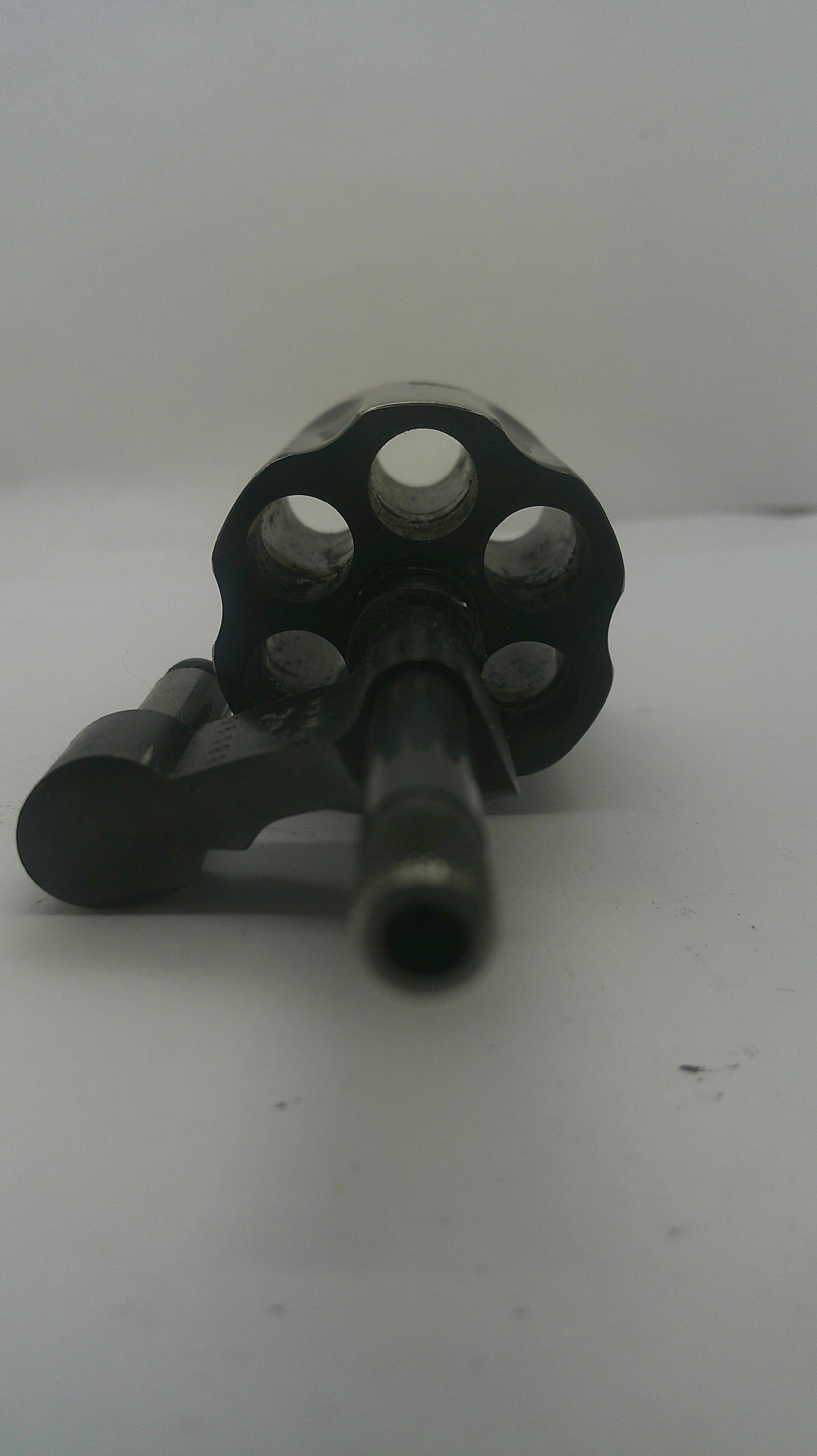 A close-up shot of a black revolver cylinder and barrel against a plain white background.