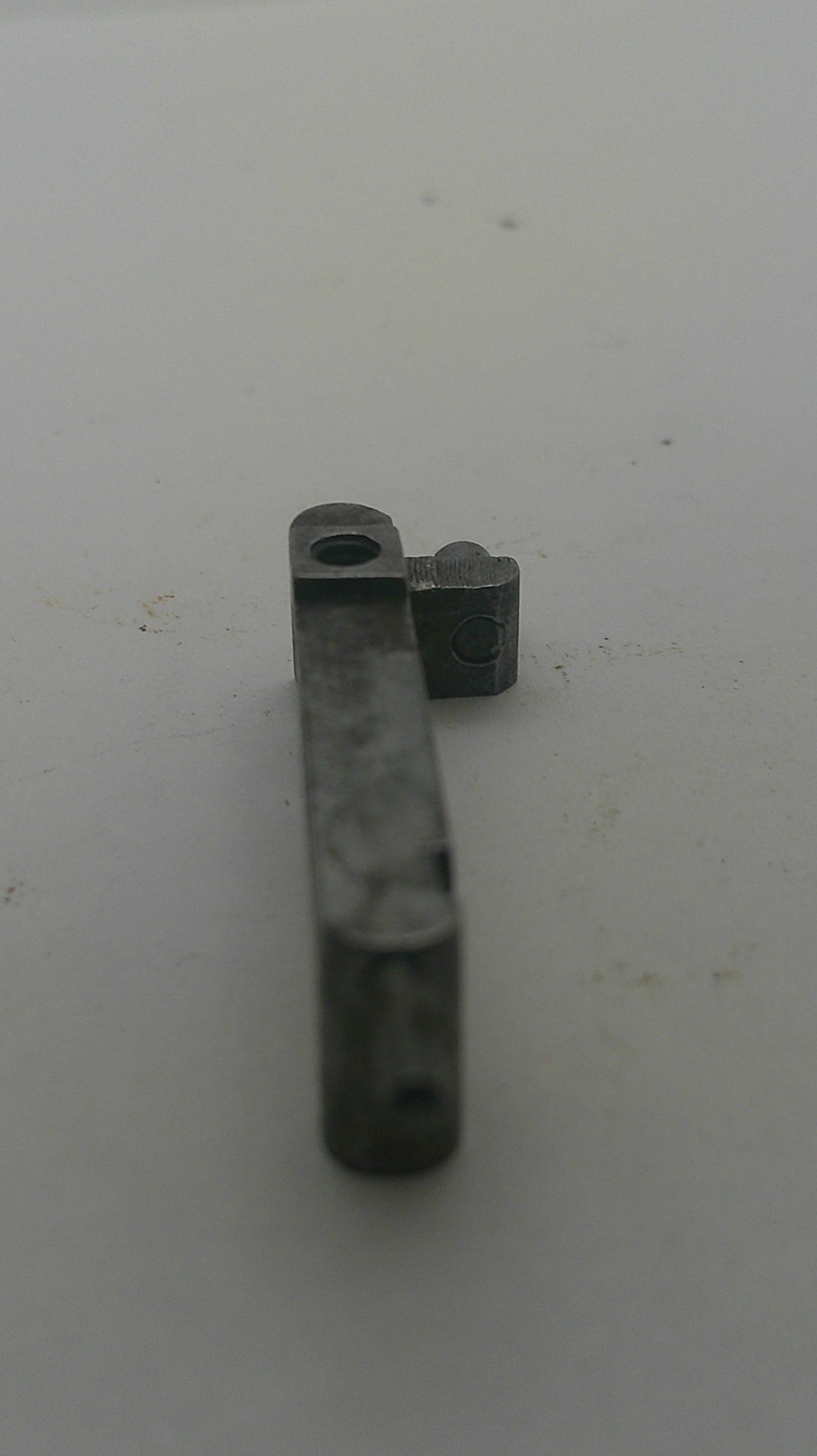 A small dark gray metal hardware component, possibly a bracket or latch piece, shown against a plain off-white background.