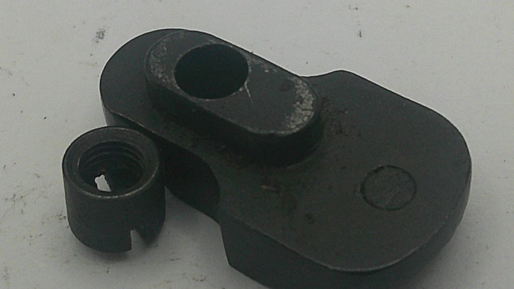 A black metal mechanical component with a threaded hole, photographed on a light gray surface.