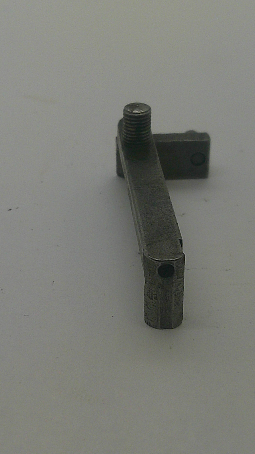 A small metal hardware component with a flat rectangular arm and a threaded bolt extending from the right side, shown against a plain light background.