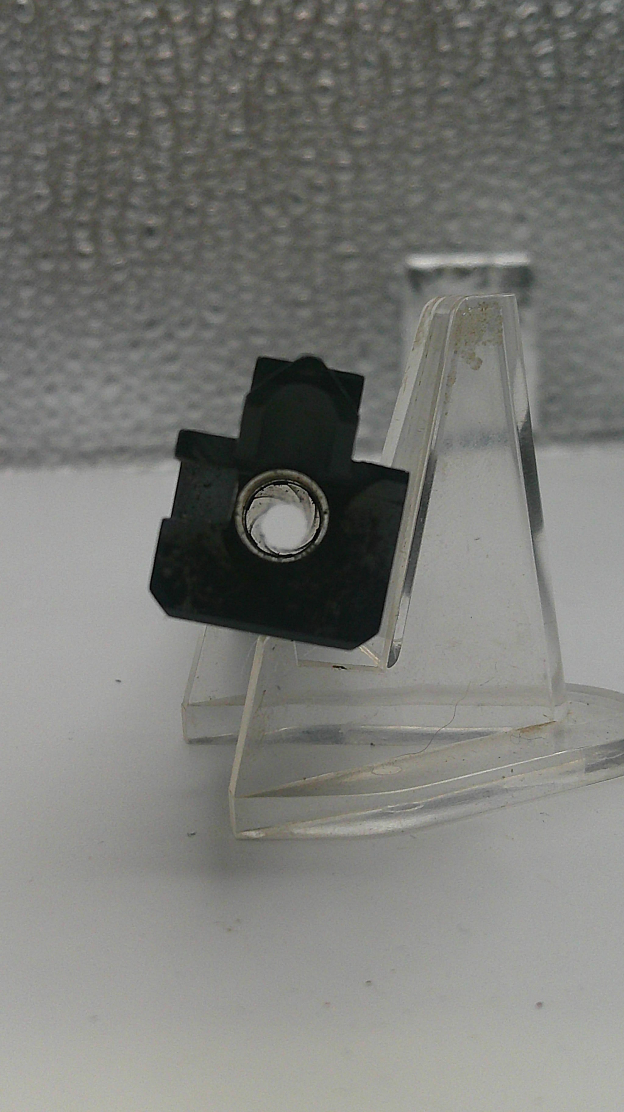 Clear plastic bracket with a black fastener on a textured gray background