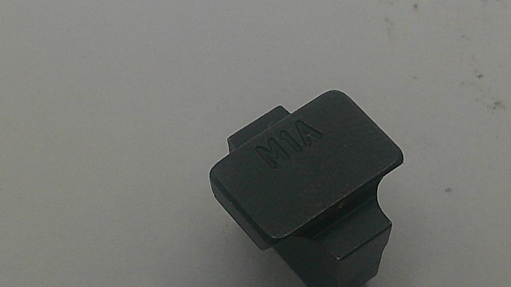A small black plastic or metal hardware component with the letters 'M1A' molded onto its top surface, photographed on a plain light gray background.