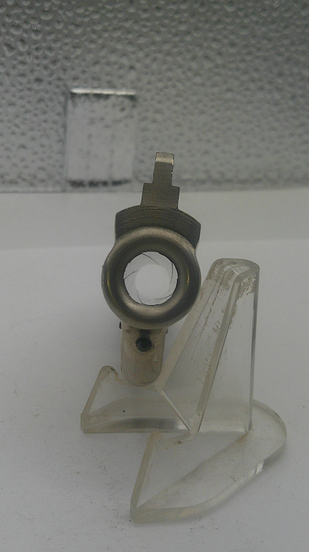 Metal valve handle with clear plastic cover on a textured wall background