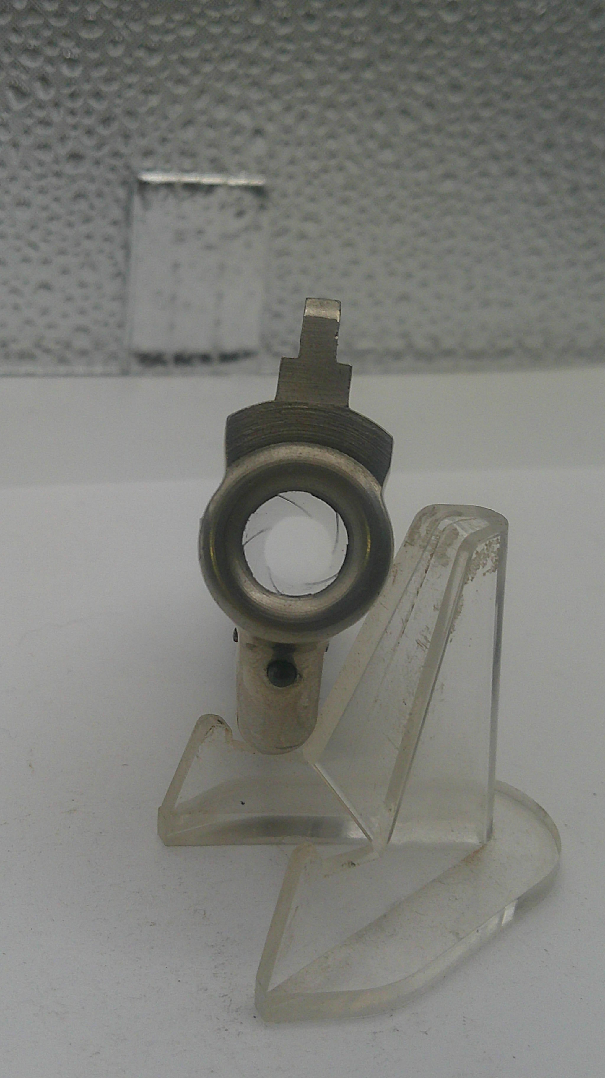 Metal valve handle with clear plastic cover on a textured wall background