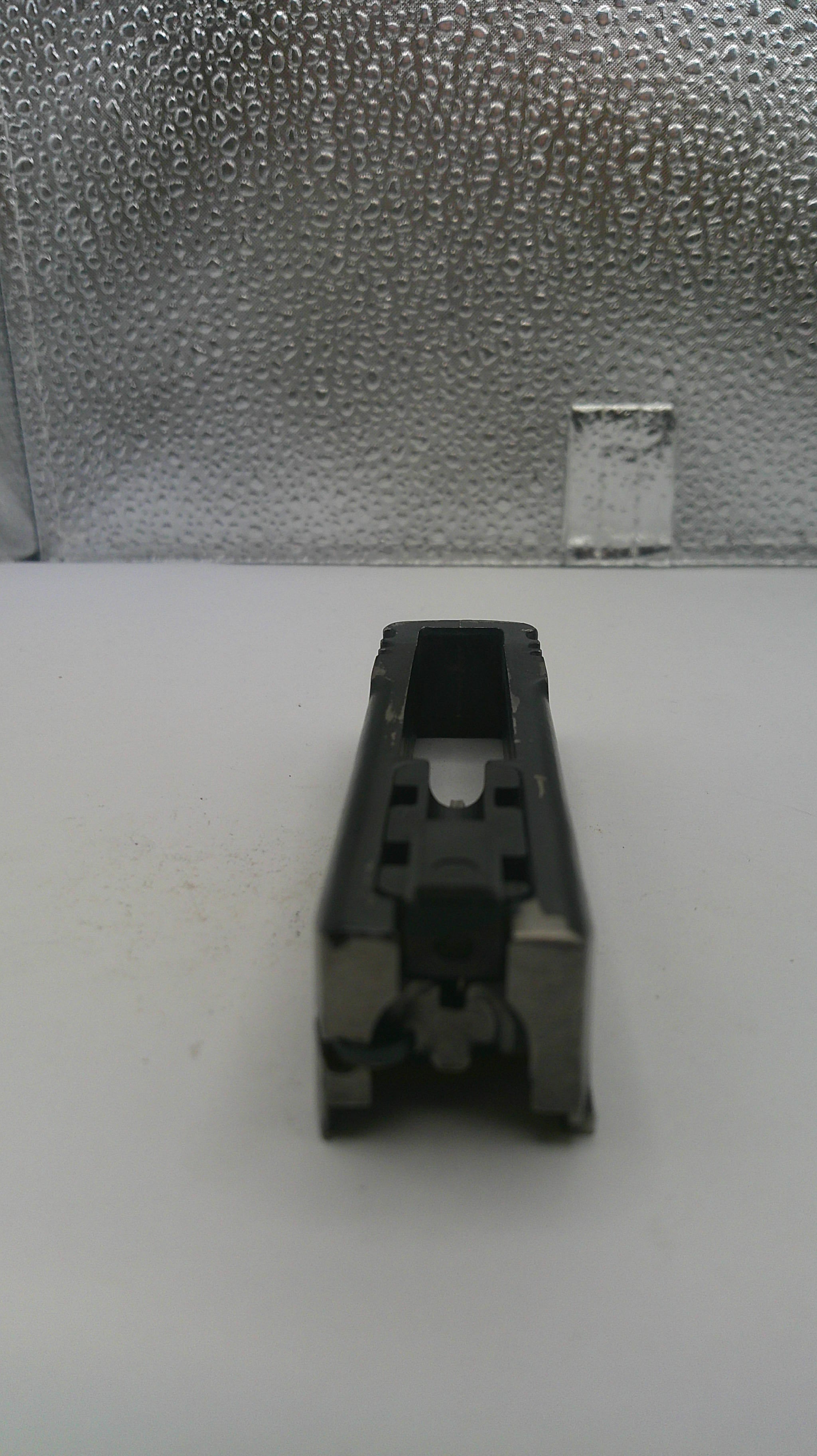 Black plastic component on a white surface with a textured gray background
