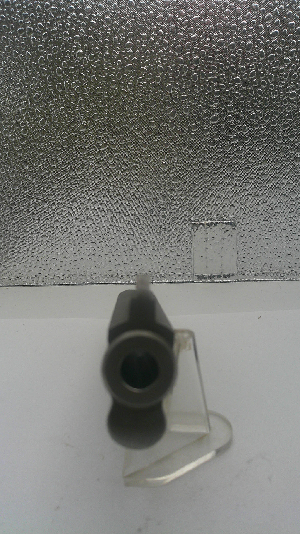 Black cylindrical object on a textured surface with a white background