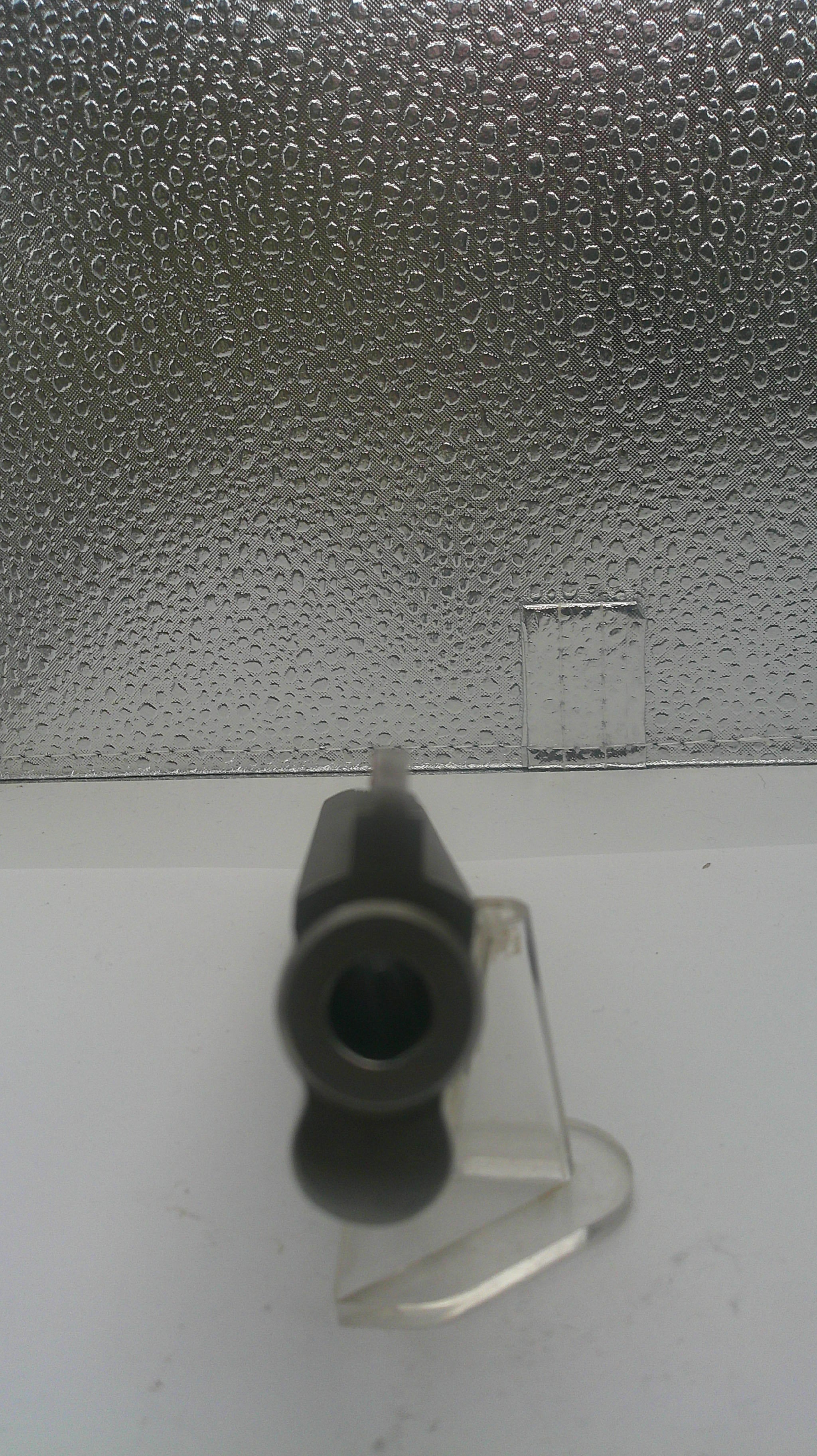 Black cylindrical object on a textured surface with a white background