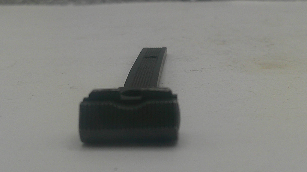 A small black plastic replacement part, possibly a cap or cover, shown on a plain light gray surface.