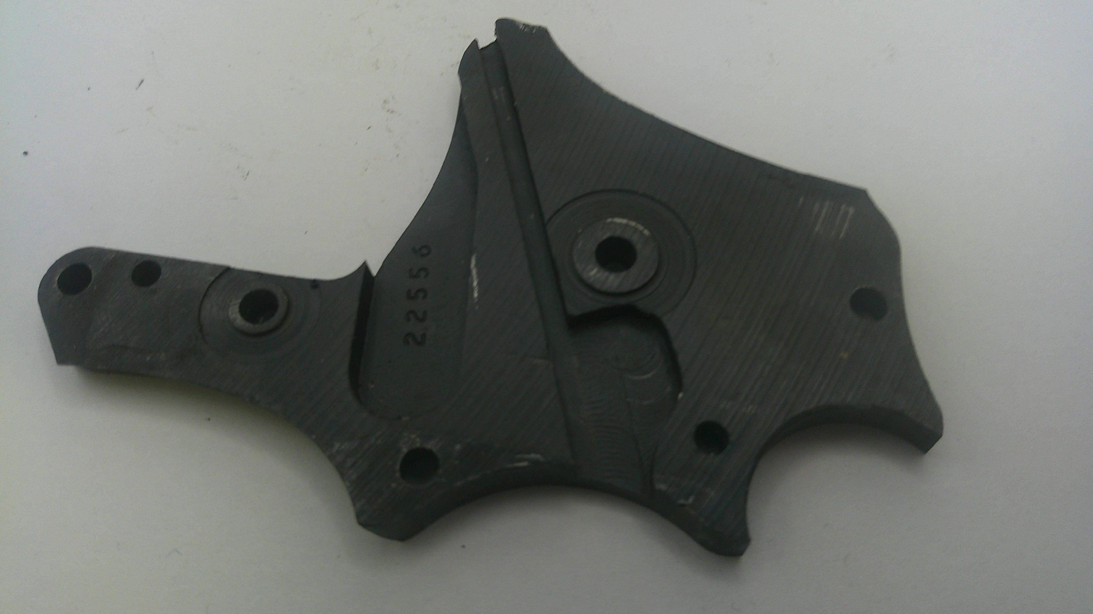 A used black metal mechanical bracket or housing component with pre-drilled mounting holes, photographed on a plain off-white background.