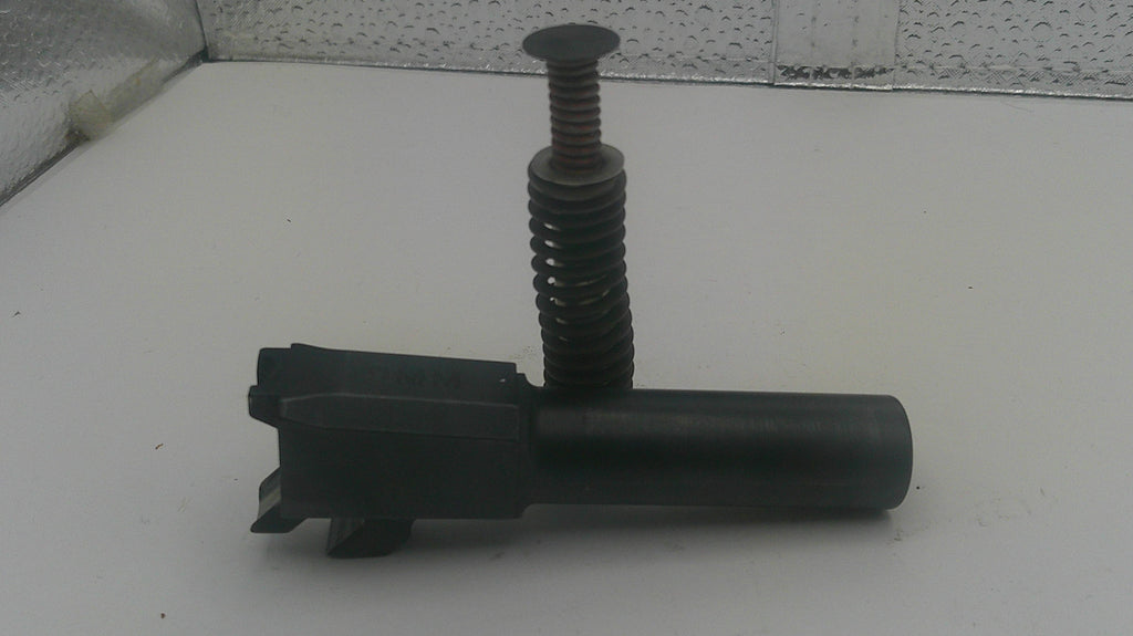 A black metal cylindrical component with a threaded vertical rod and a flat circular top, photographed on a white surface against a textured gray background.