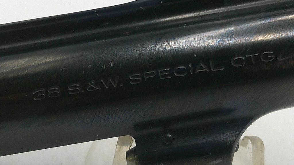 Close-up of a black firearm barrel with engraved text on a white background