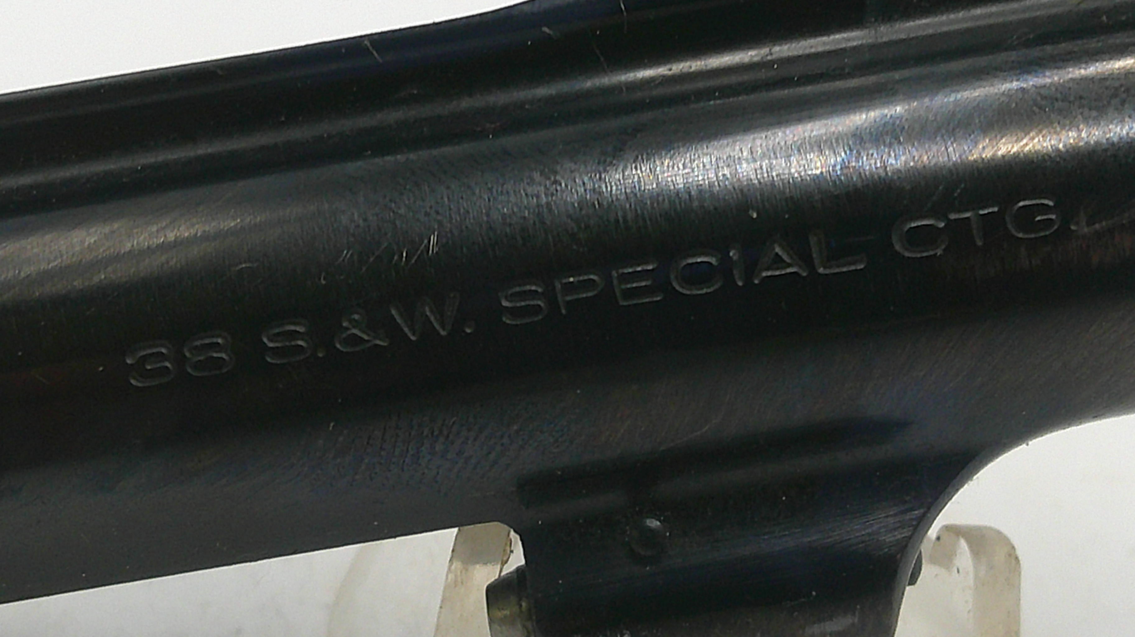 Close-up of a black firearm barrel with engraved text on a white background